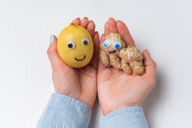 Komik yüzlü limon ve zencefil palmiyelerde yatar. Beyaz arka plan. Sağlıklı ürünler.