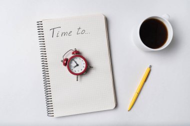 Üzerinde yazı olan defter zamanı. Not defteri ve klasik çalar saat. Planlama ve kahve.