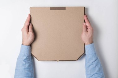 Erkeklerin elindeki pizza kutusunun üst görüntüsü. Beyaz arka plan. Eve yiyecek teslimatı kavramı.