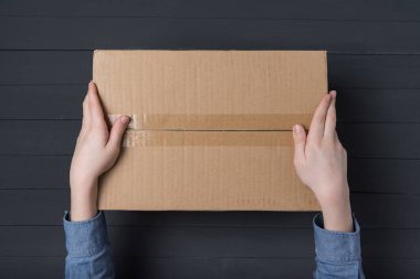 Çocuk eller büyük bir karton kutu tutuyor. Eve paket teslimatı. Üst görünüm.