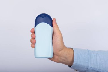 Bir şişe şampuan, saç kremi ya da beyaz arka planda erkek elinde losyon. Uzayı kopyala, taklit et.