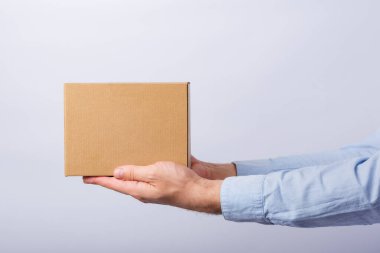Beyaz arka planda kol mesafesinde bir kutu tutan adam. Kare karton kutu. Paketlerin teslimatı. Yan görünüm