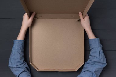 Çocukların elinde boş bir pizza kutusu var. Siyah arka plan. Üst Manzara. Boşluğu kopyala