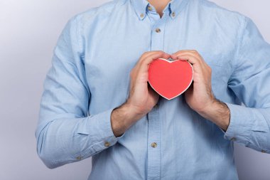 Erkek eller kalp şeklinde kırmızı kutuyu tutuyor. Sevgili için bir hediye. Sevgililer Günü hediyesi..