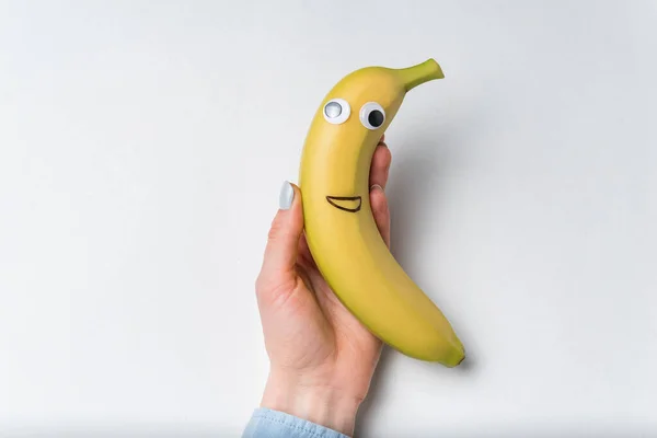 Mano Sosteniendo Plátano Con Una Cara Divertida Sobre Fondo Blanco — Foto de Stock