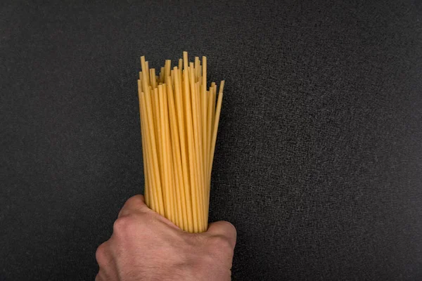 Ruka Drží Nevařené Špagety Šedém Pozadí Suché Nevařené Těstoviny Pro — Stock fotografie