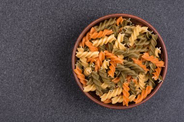 Fusilli pastası gri arka planda kasede. Çiğ İtalyan makarnası. Üst Manzara. Uzayı kopyala Şablon. Model.