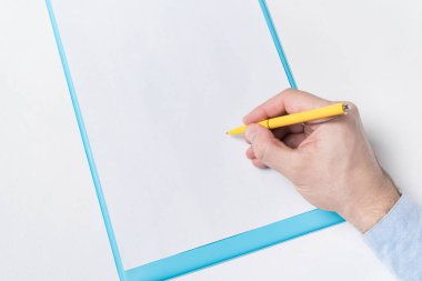 Boş bir kağıt üzerinde kalemle erkek eli. Adam kağıda imza atıyor. Üst görünüm.