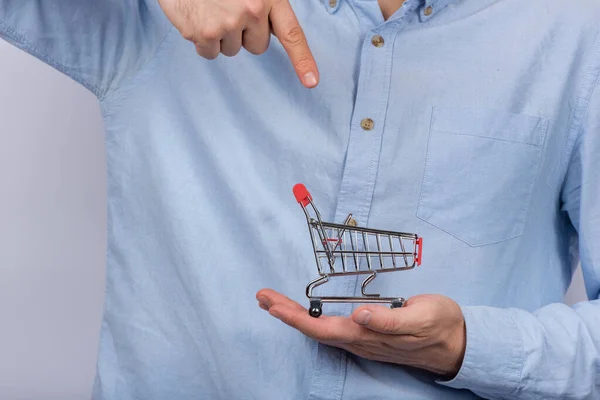男はショッピングカートを保持し 指で指しています 便利なショッピングコンセプト — ストック写真