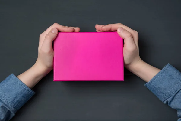 Mãos Criança Segurando Caixa Presente Rosa Fundo Preto Vista Superior — Fotografia de Stock