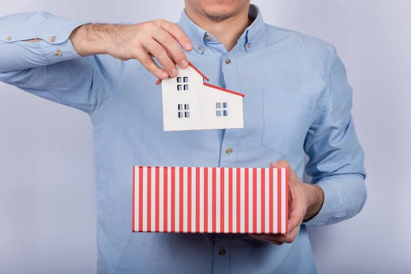 Stock image Man puts a model house in a gift box. Model home in opened cardboard box.