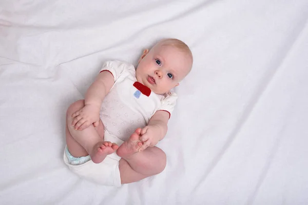 Cute Baby Girl Stares Into The Camera Newborn In Diapers On White Sheets Top View Beautiful Small Stock Photo