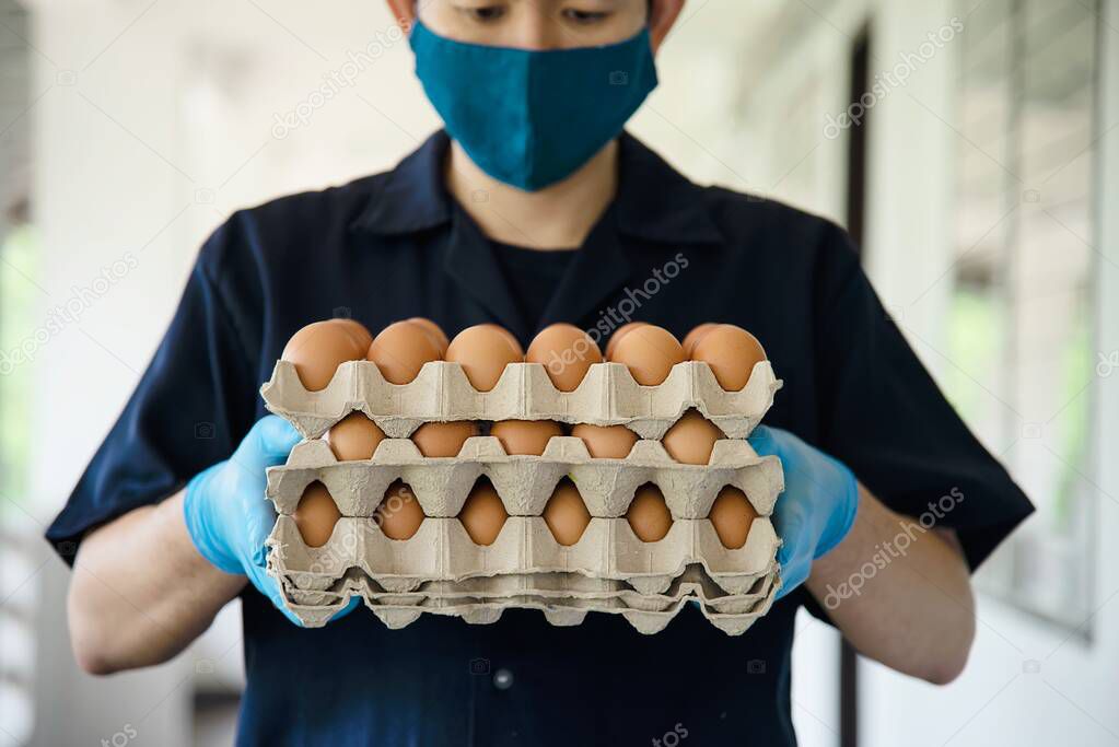 A man deliver 3 layers eggs tray for customer while putting sanitary glove - people with clean delivery food concept