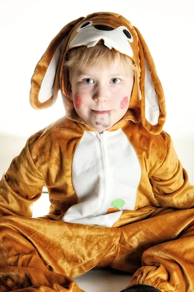 Маленький хлопчик, одягнений для кролика, сидить на землі — стокове фото