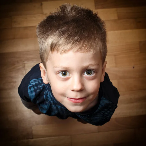 Хлопчик дивиться прямо на камеру на дерев'яній підлозі — стокове фото
