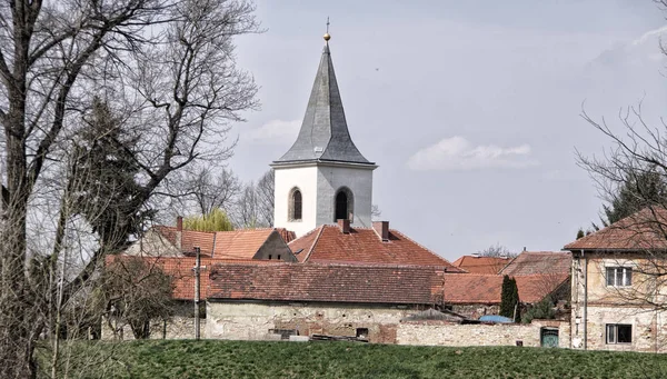 Gamla byn hus med sprucken fasad och låg kyrktornet — Stockfoto