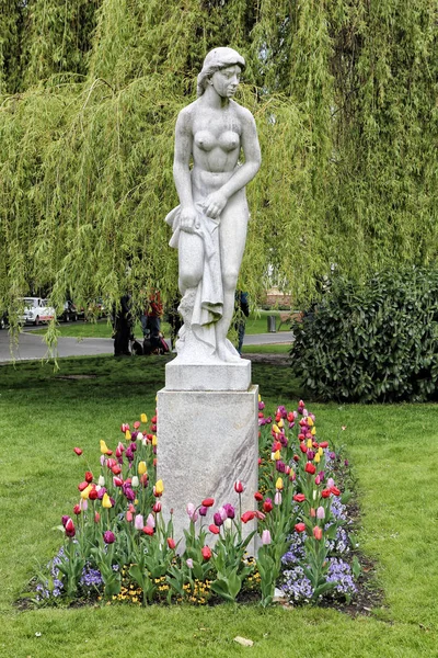 Estatua de la chica desnuda en medio de tulipanes — Foto de Stock