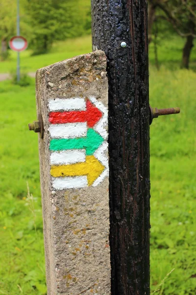 Tourist sign colorful arrows on the old wooden pole grounding — Stock Photo, Image
