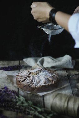 İki el bir pasta ahşap bir masa üzerinde uzanan. Bir bardak süt. derin bir tabak içinde kiraz. Laaanda bir demet.