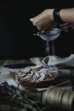 İki el bir pasta ahşap bir masa üzerinde uzanan. Bir bardak süt. derin bir tabak içinde kiraz. Laaanda bir demet.