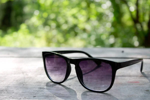 Glasses on a wooden table in a forest — Stock Photo, Image