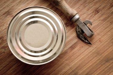 tin can and can opener on wooden background clipart