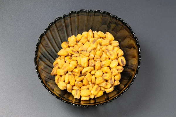 Pražené kukuřičné ořechy v talíři na tmavém pozadí — Stock fotografie