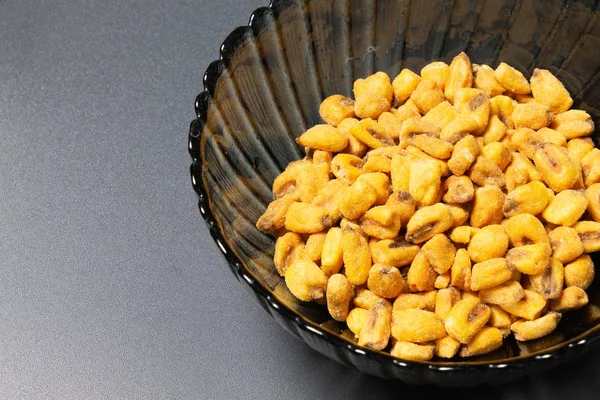 Roasted corn nuts in plate on dark background