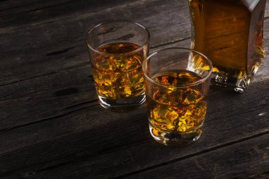 Koyu ahşap arka plan üzerinde iki kadeh viski. Tonlama