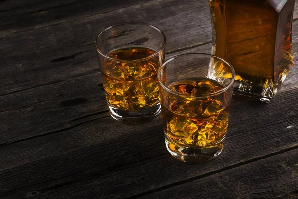 Koyu ahşap arka plan üzerinde iki kadeh viski. Tonlama