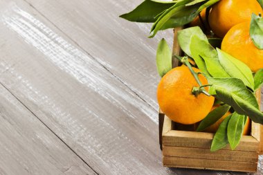 Mandalina ile karanlık bir ahşap zemin üzerine Yeşil broşürler. Uzay kopyalayın. Gıda arka plan. Tonlama.