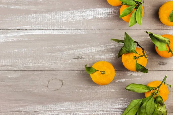 Tangerines with green leaflets on a dark wooden background. Top view, copy space. Food background.