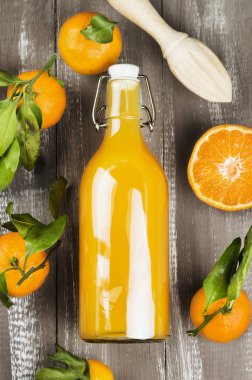 Şişe mandalina suyu ve ahşap bir zemin üzerine taze meyve