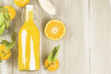 Şişe mandalina suyu ve ahşap bir zemin üzerine taze meyve