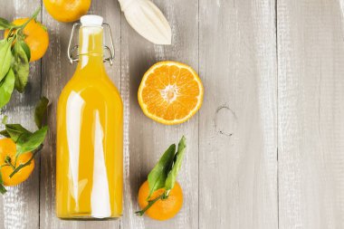 Şişe mandalina suyu ve ahşap bir zemin üzerine taze meyve