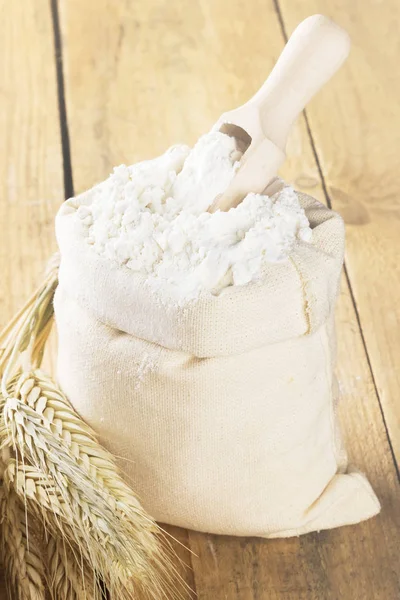 Flour in bag and wheat ears on a wooden background. Toning