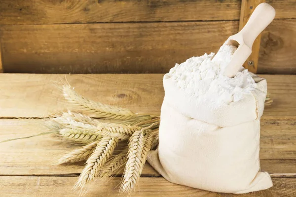 Flour in bag and wheat ears on a wooden background. Copy space. — Stock Photo, Image