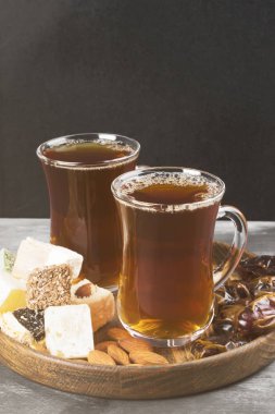 Siyah çay, oryantal tatlılar, tarihleri ve karanlık bir arka plan üzerinde fındık.