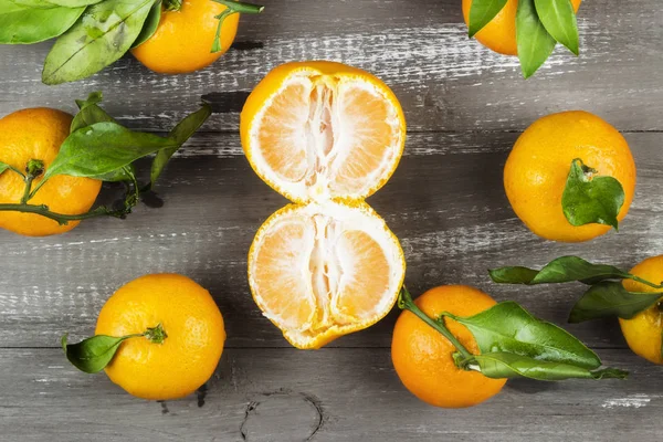 Tangerines with green leaflets on a dark wooden background. Top