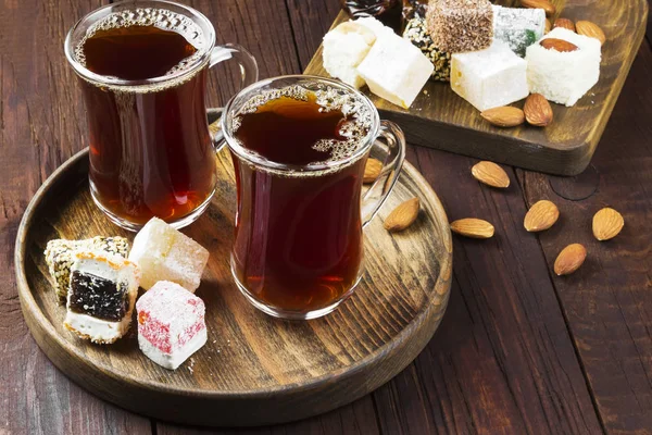 Zwarte thee, oosterse snoepjes, datums en noten op een donkere houten rug — Stockfoto