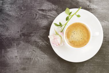 Espresso kahve beyaz Kupası ve karanlık bir arka plan üzerinde pembe bir gül. Görünümü en çok, uzay kopyalayın. Gıda arka plan. Tonlama