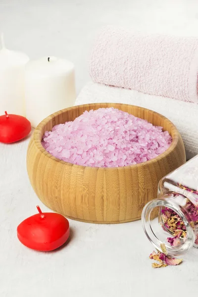 Sal de baño con aroma a rosa en un cuenco de madera, pétalos y rosa fresca, toallas y velas sobre fondo blanco . — Foto de Stock