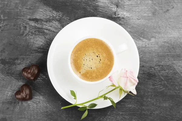 Café expresso em uma xícara branca, rosa e chocolates em um fundo escuro. Vista superior. Fundo alimentar — Fotografia de Stock