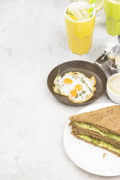 Завтрак - тост из ржаного хлеба с авокадо, жареные яйца, лимонад и кофе на светлом фоне. Принято. Питание. Тонирование . — стоковое фото