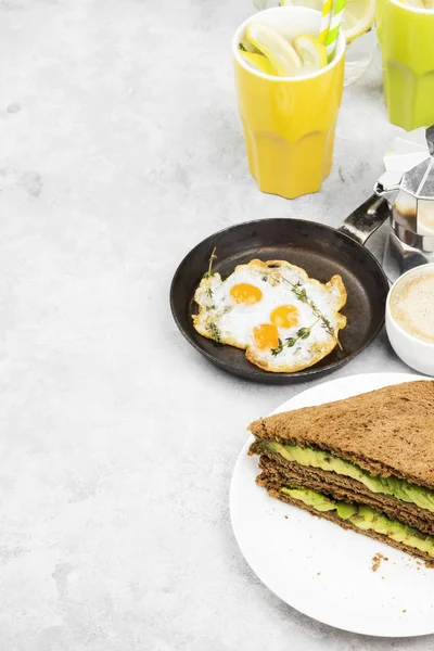 Café da manhã - um brinde de pão de centeio com abacate, ovos fritos, limonada e café em um contexto leve. Espaço para cópia. Fundo alimentar — Fotografia de Stock