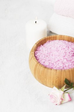 Banyo tuzu ile ahşap bir kase, yaprakları ve taze bir pembe Gül gül kokusu, havlu ve beyaz zemin üzerine mumlar. Kopya alanı.