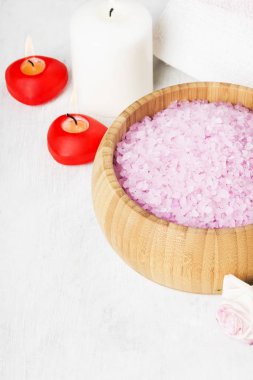 Banyo tuzu ile ahşap bir kase, yaprakları ve taze bir pembe Gül gül kokusu, havlu ve beyaz zemin üzerine mumlar. Kopya alanı