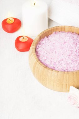 Banyo tuzu ile ahşap bir kase, yaprakları ve taze bir pembe Gül gül kokusu, havlu ve beyaz zemin üzerine mumlar. Uzay kopyalayın. Tonlama.