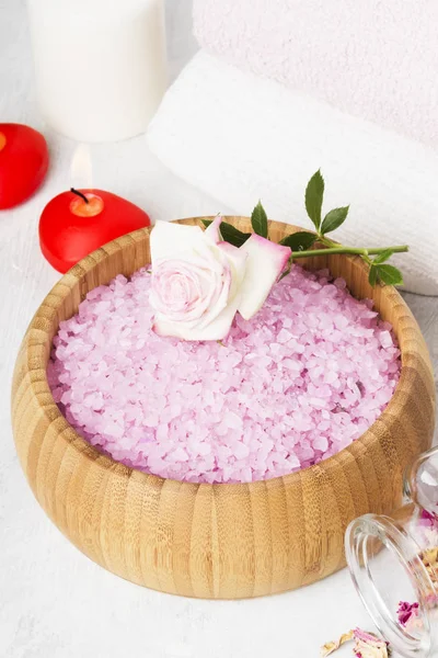 Sal de baño con aroma a rosa en un cuenco de madera, pétalos y rosa fresca, toallas y velas sobre fondo blanco — Foto de Stock