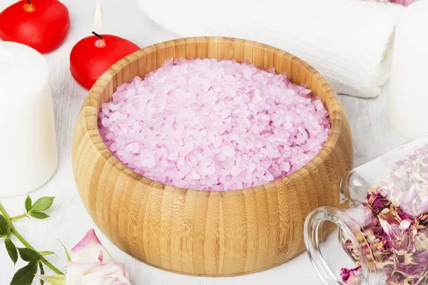 Sal de baño con aroma a rosa en un cuenco de madera, pétalos y rosa fresca, toallas y velas sobre fondo blanco . — Foto de Stock